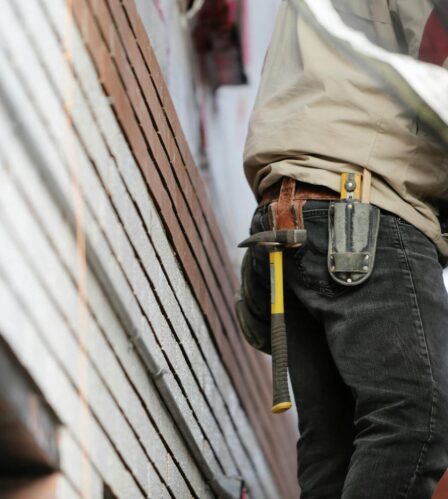 Photo by Life Of Pix Close-up of a construction worker with hammer and tools, focused on the job.